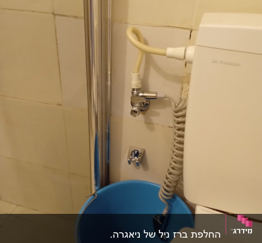 דלי כחול ליד צינור מים ומיכל שירותים